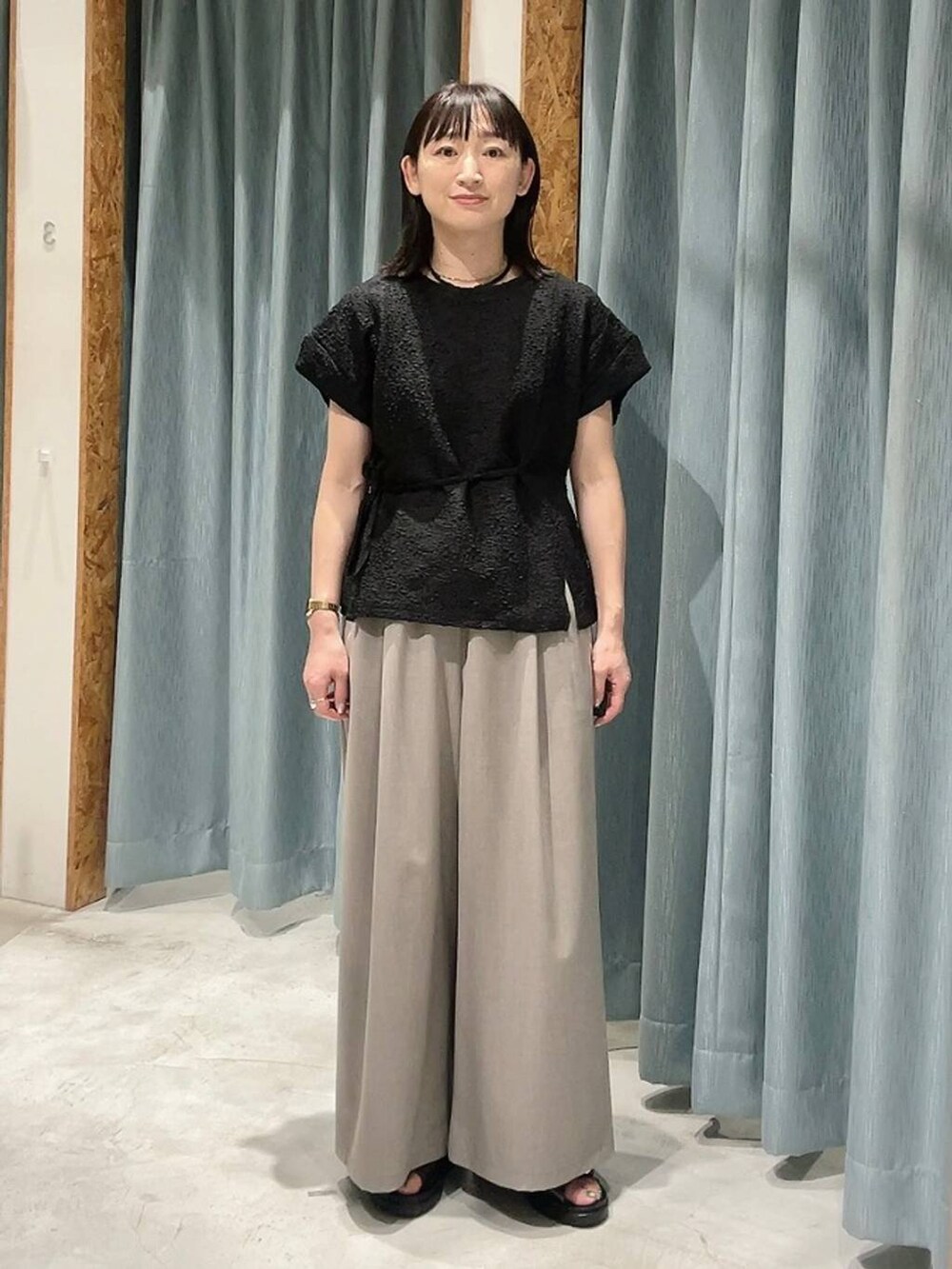 ブラウン系のサンダル、ベージュ系のその他パンツ、ブラック系のTシャツ/カットソーを着用したレディースの夏コーディネートの7枚目の写真