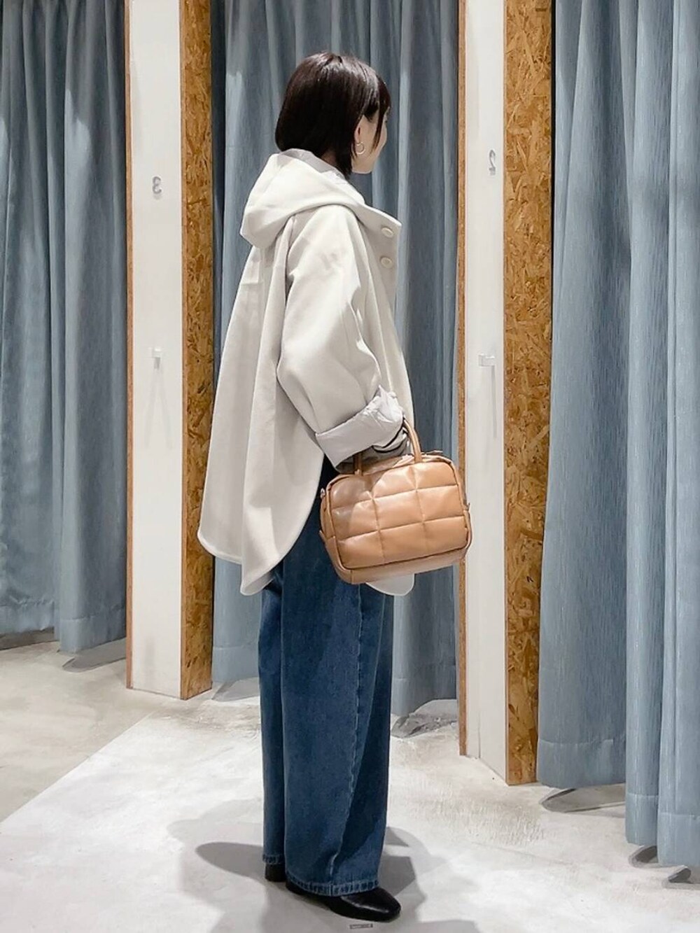 ホワイト系のポンチョ、ホワイト系のニット/セーター、ブルー系のデニムパンツを着用したレディースの秋コーディネートの4枚目の写真