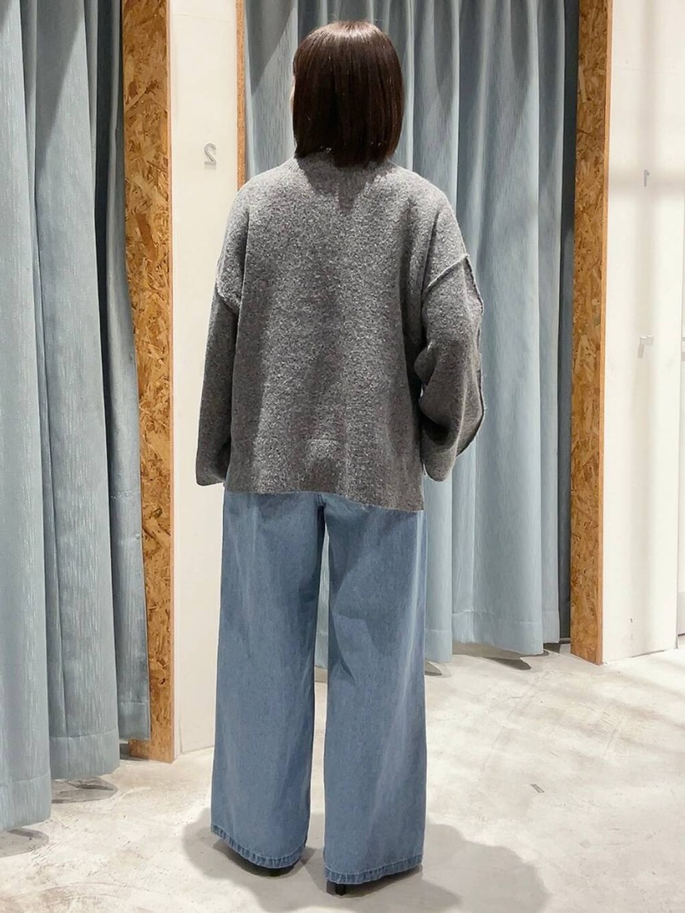 ブラック系のパンプス、グレー系のニット/セーター、ブルー系のデニムパンツを着用したレディースの冬コーディネートの3枚目の写真