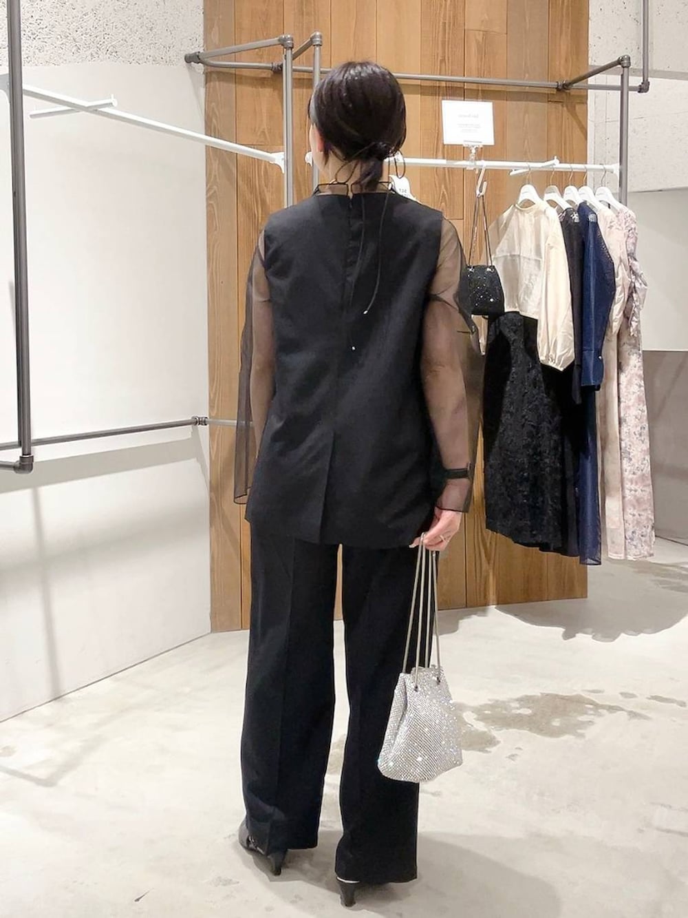 シルバー系のショルダーバッグ、ブラック系のパンプス、ブラック系のパンツドレスを着用したレディースの秋コーディネートの4枚目の写真