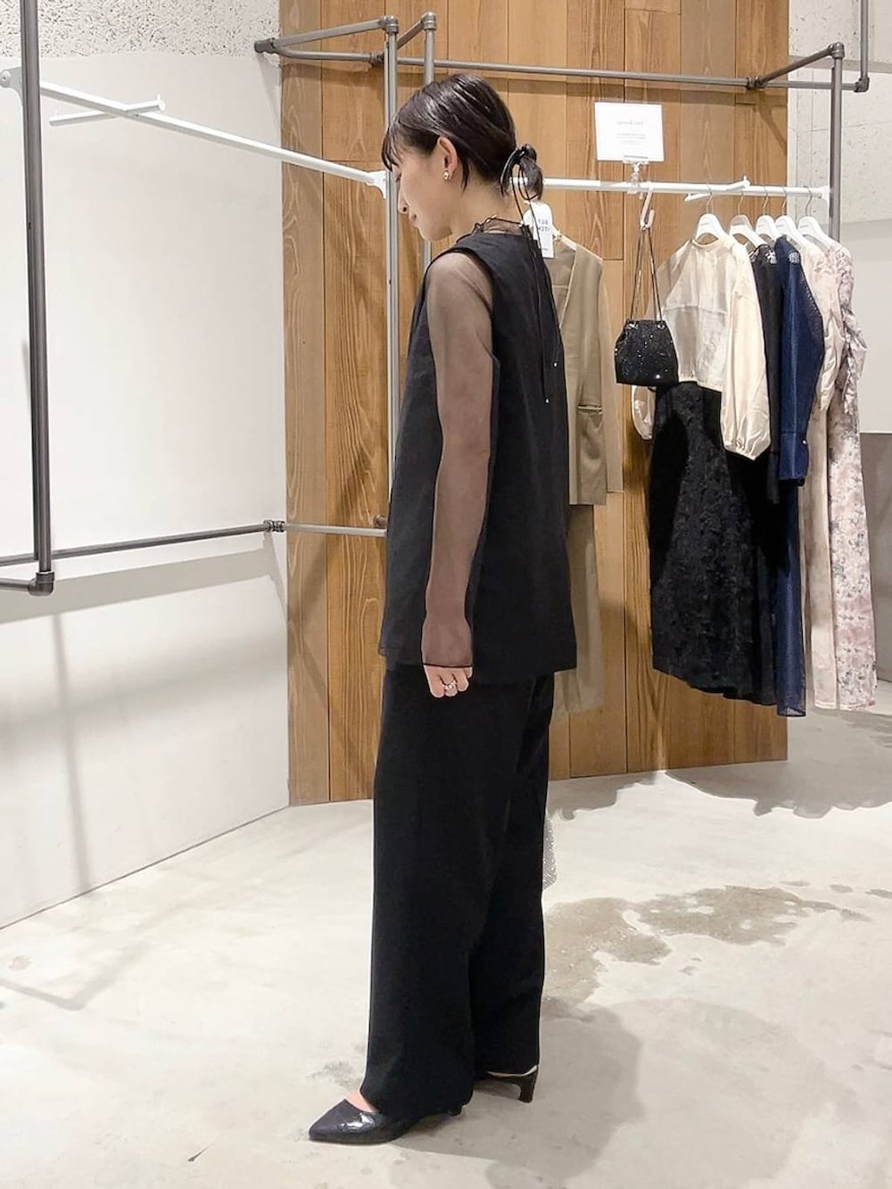 シルバー系のショルダーバッグ、ブラック系のパンプス、ブラック系のパンツドレスを着用したレディースの秋コーディネートの5枚目の写真