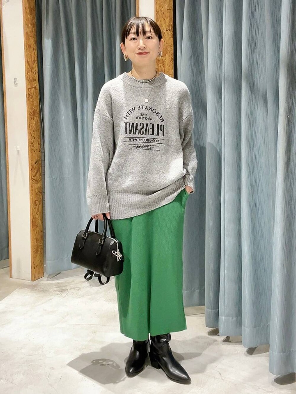 ブラック系のボストンバッグ、ブラック系のブーツ、グレー系のニット/セーターを着用したレディースの冬コーディネートの7枚目の写真