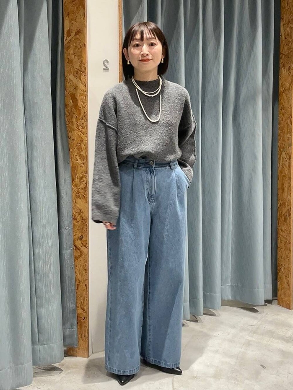 ブラック系のパンプス、グレー系のニット/セーター、ブルー系のデニムパンツを着用したレディースの冬コーディネートの8枚目の写真