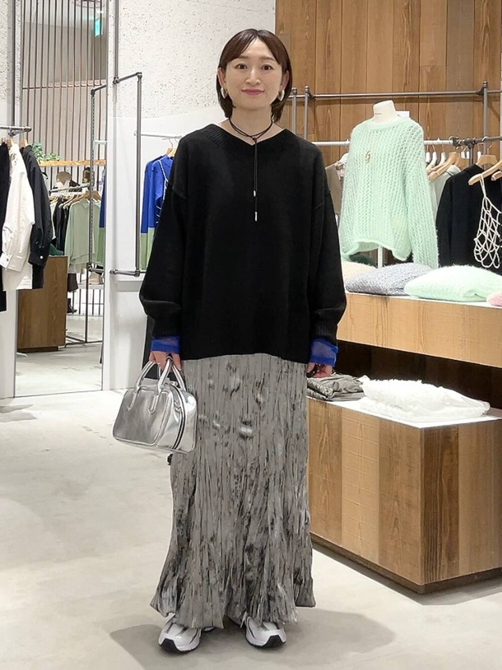 シルバー系のボストンバッグ、ブラック系のニット/セーター、ホワイト系のTシャツ/カットソーを着用したレディースの秋コーディネートの6枚目の写真