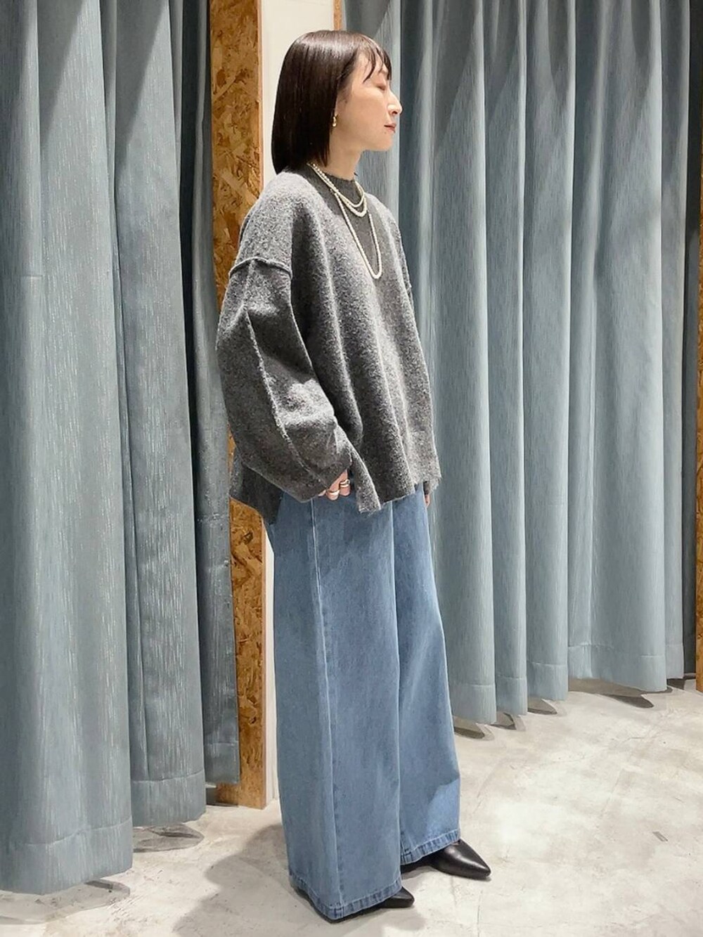 ブラック系のパンプス、グレー系のニット/セーター、ブルー系のデニムパンツを着用したレディースの冬コーディネートの2枚目の写真