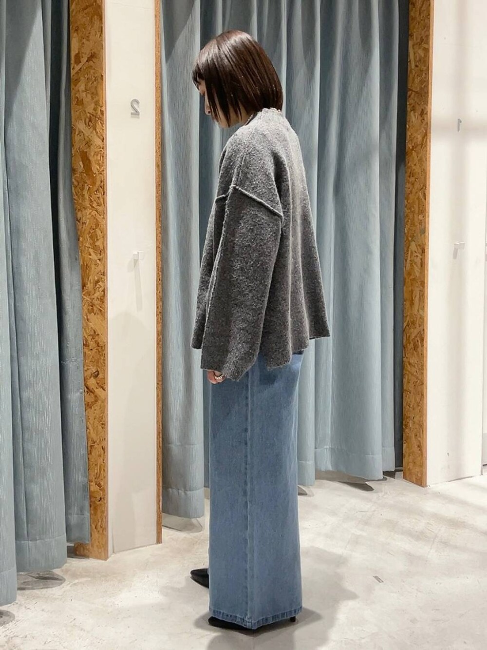 ブラック系のパンプス、グレー系のニット/セーター、ブルー系のデニムパンツを着用したレディースの冬コーディネートの4枚目の写真