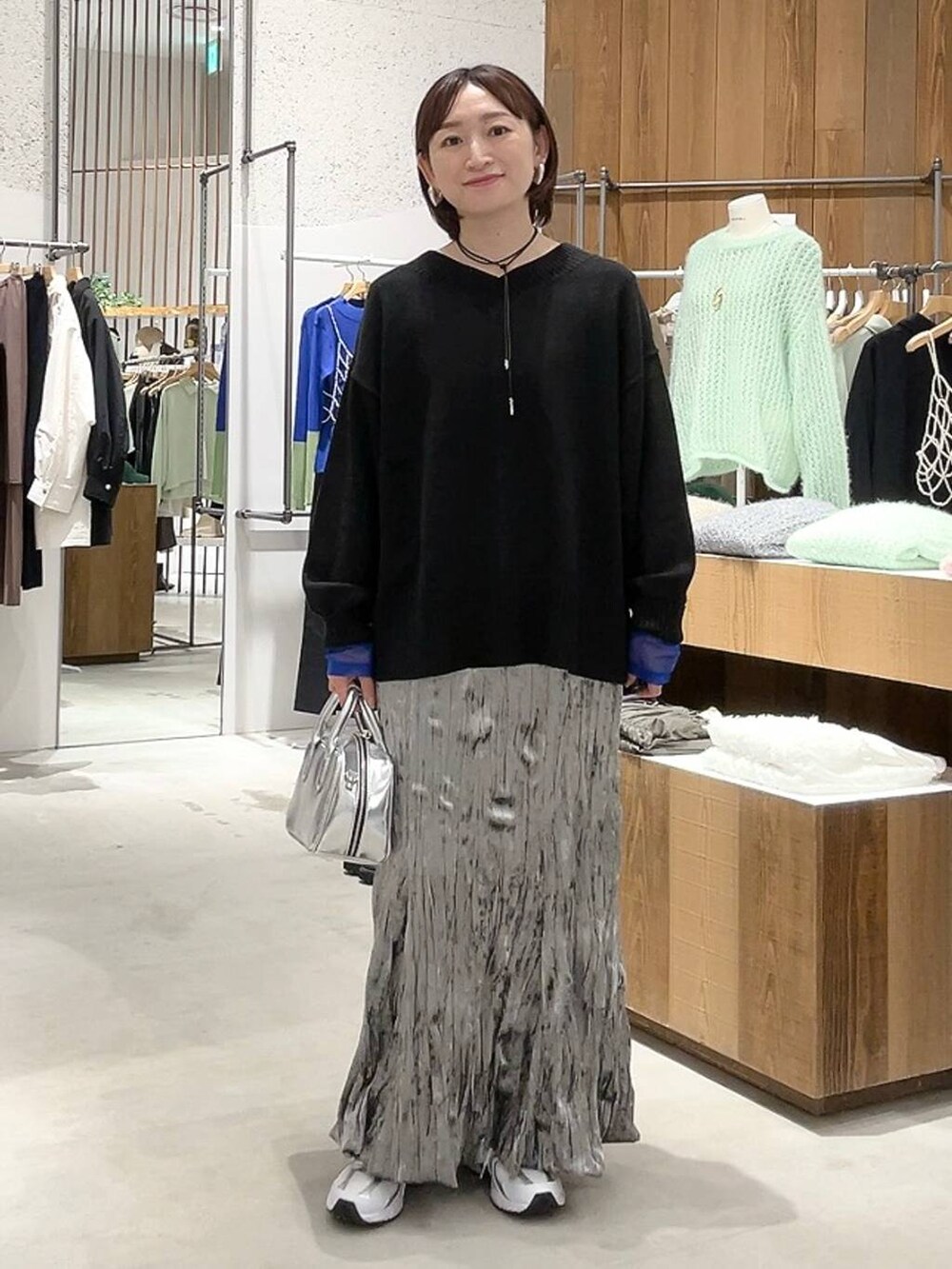 シルバー系のボストンバッグ、ブラック系のニット/セーター、ホワイト系のTシャツ/カットソーを着用したレディースの秋コーディネートの2枚目の写真