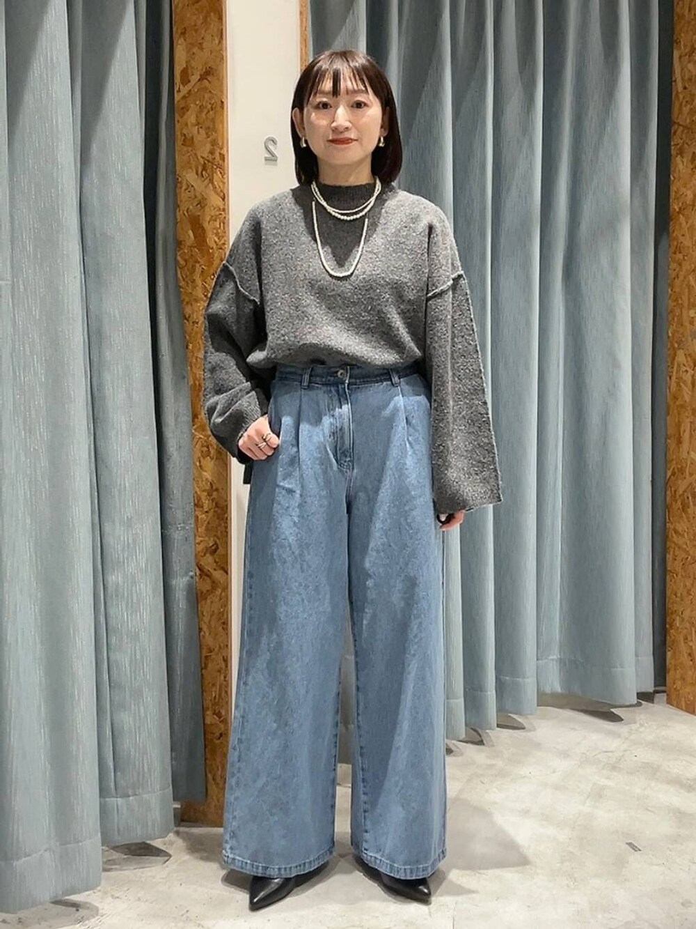 ブラック系のパンプス、グレー系のニット/セーター、ブルー系のデニムパンツを着用したレディースの冬コーディネートの5枚目の写真