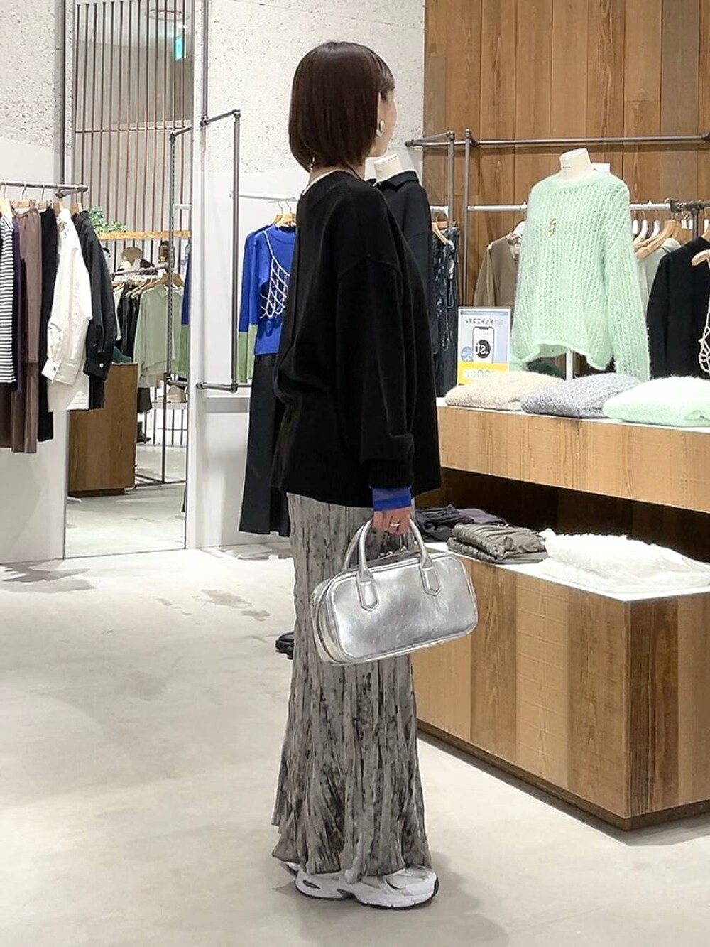 シルバー系のボストンバッグ、ブラック系のニット/セーター、ホワイト系のTシャツ/カットソーを着用したレディースの秋コーディネートの3枚目の写真