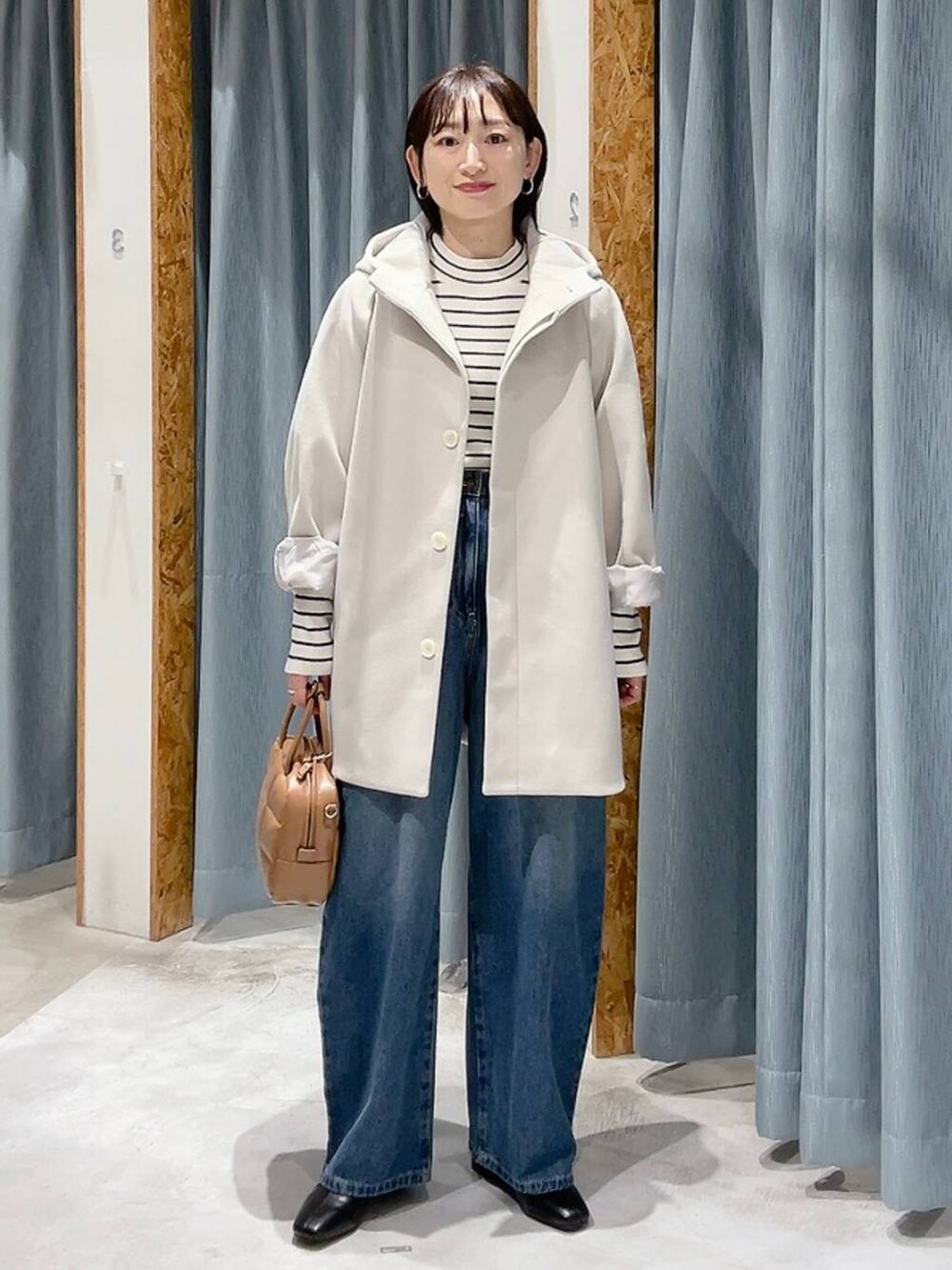 ホワイト系のポンチョ、ホワイト系のニット/セーター、ブルー系のデニムパンツを着用したレディースの秋コーディネートの2枚目の写真