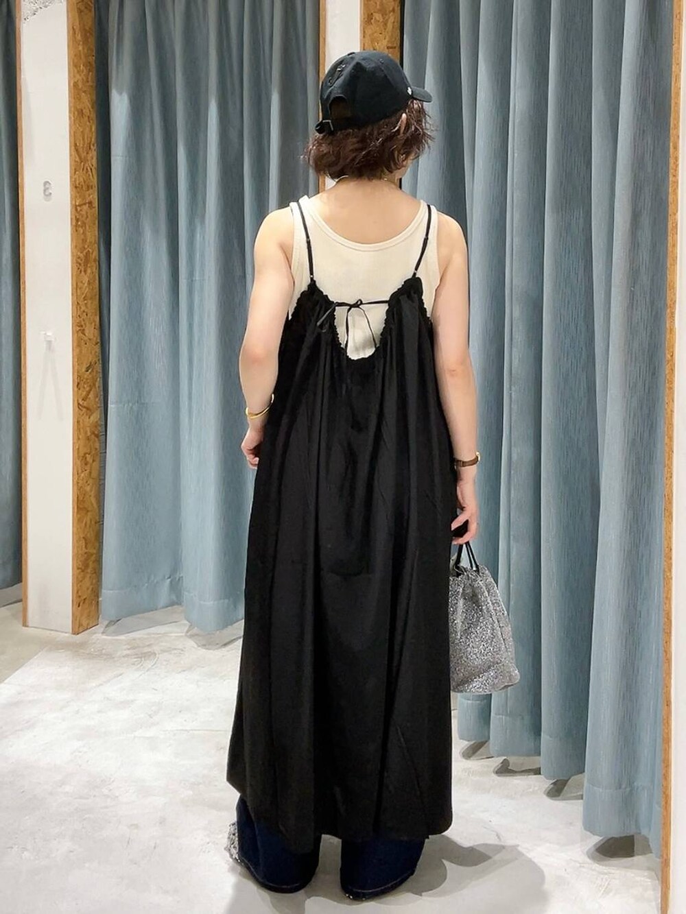 グレー系のショルダーバッグ、ブルー系のデニムパンツ、ホワイト系のタンクトップを着用したレディースの夏コーディネートの4枚目の写真