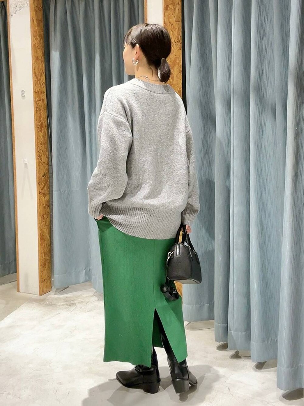 ブラック系のボストンバッグ、ブラック系のブーツ、グレー系のニット/セーターを着用したレディースの冬コーディネートの6枚目の写真