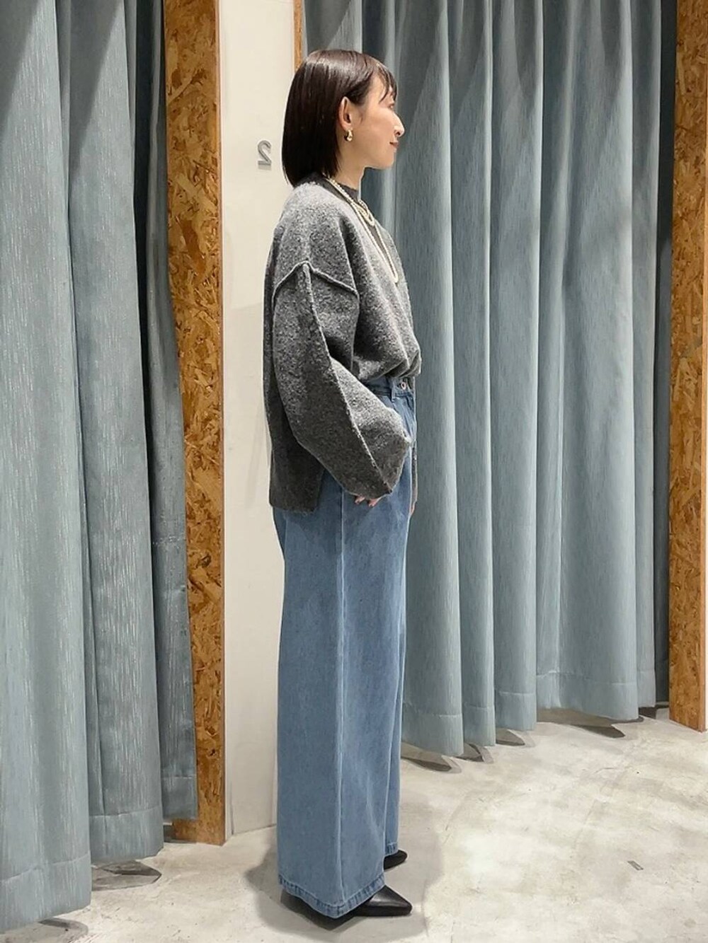 ブラック系のパンプス、グレー系のニット/セーター、ブルー系のデニムパンツを着用したレディースの冬コーディネートの6枚目の写真