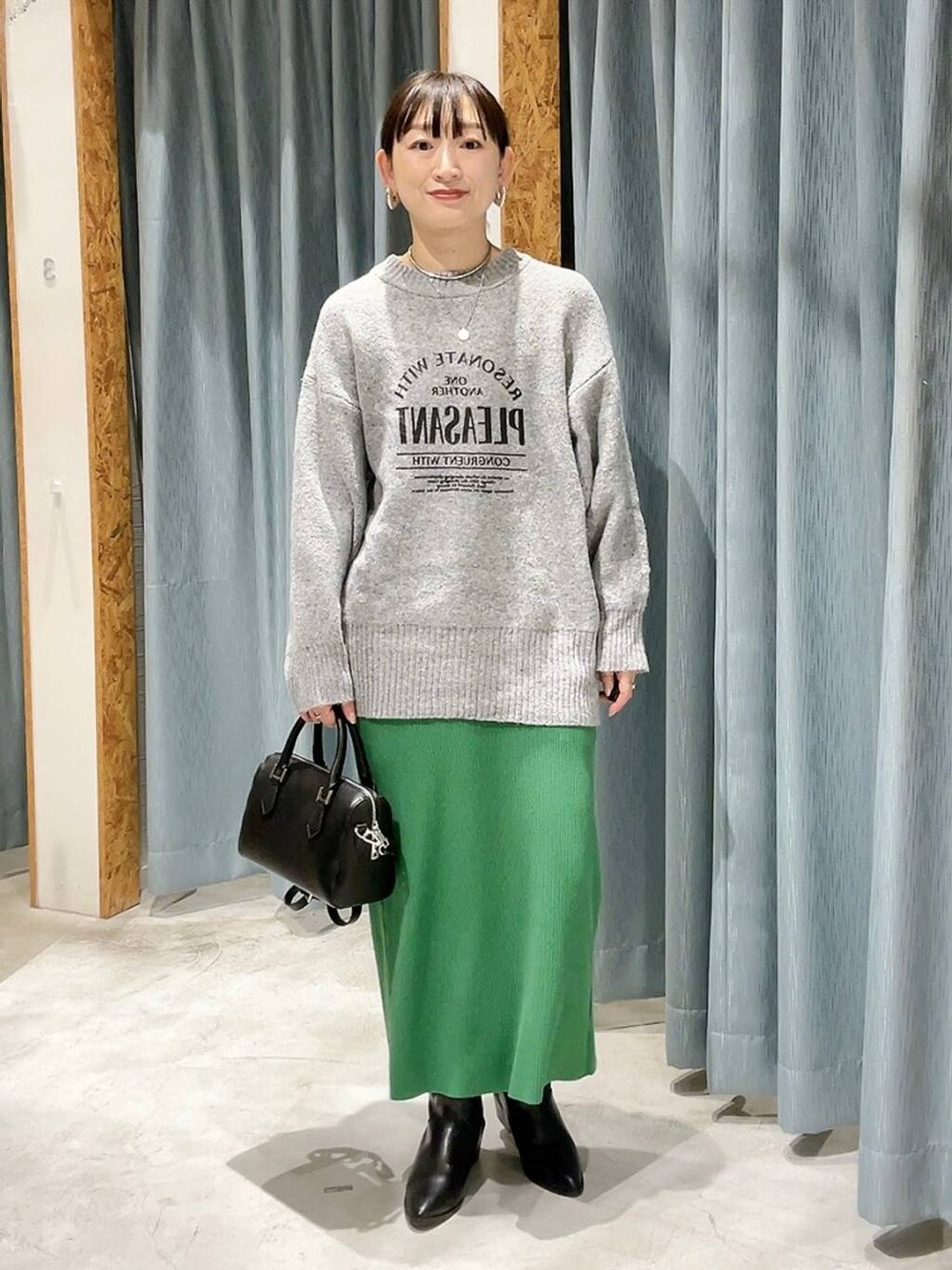 ブラック系のボストンバッグ、ブラック系のブーツ、グレー系のニット/セーターを着用したレディースの冬コーディネートの4枚目の写真