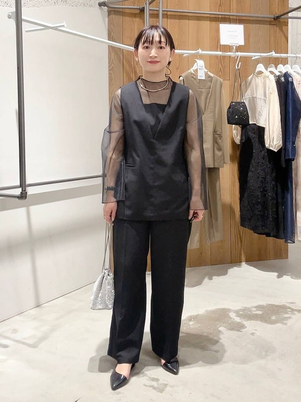 シルバー系のショルダーバッグ、ブラック系のパンプス、ブラック系のパンツドレスを着用したレディースの秋コーディネートの2枚目の写真