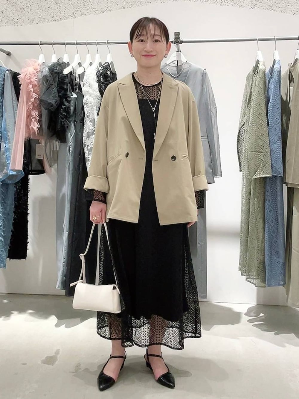 ベージュ系のテーラードジャケット、ブラック系のドレス、ゴールド系のネックレスを着用したレディースの春コーディネートの7枚目の写真