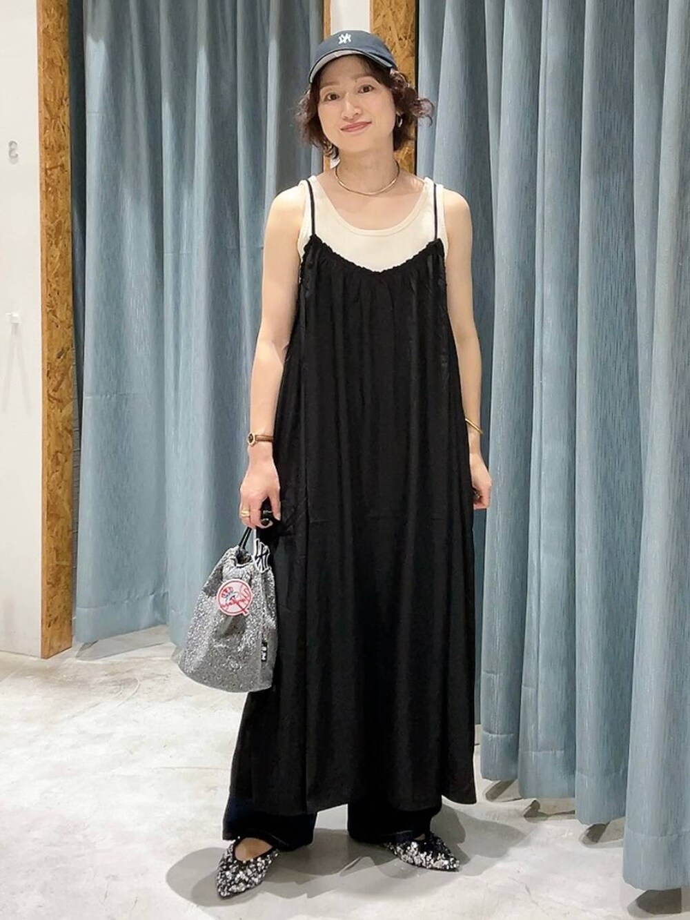 グレー系のショルダーバッグ、ブルー系のデニムパンツ、ホワイト系のタンクトップを着用したレディースの夏コーディネートの5枚目の写真