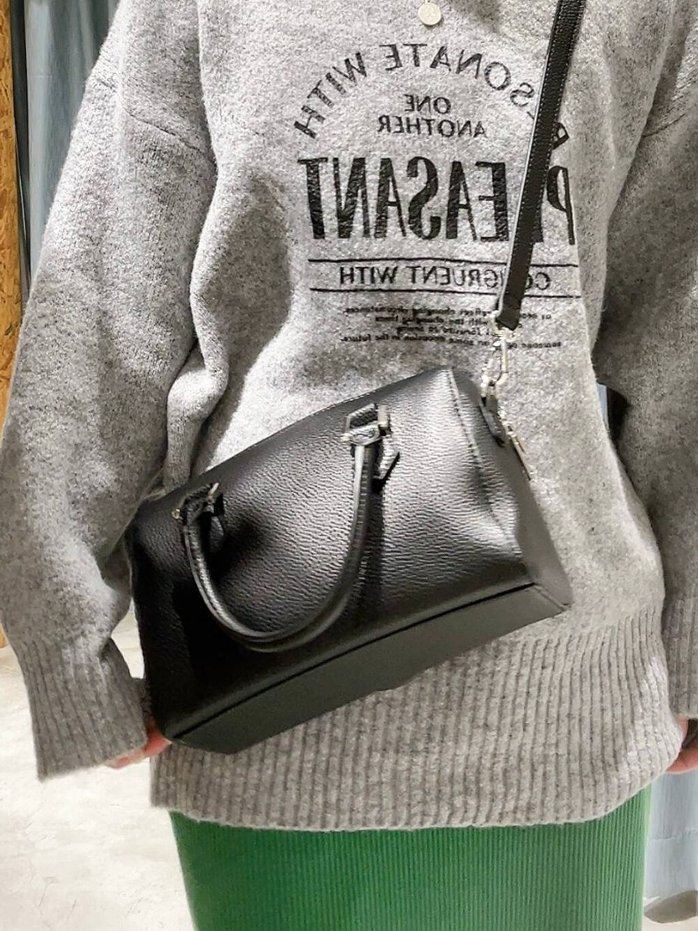 ブラック系のボストンバッグ、ブラック系のブーツ、グレー系のニット/セーターを着用したレディースの冬コーディネートの2枚目の写真