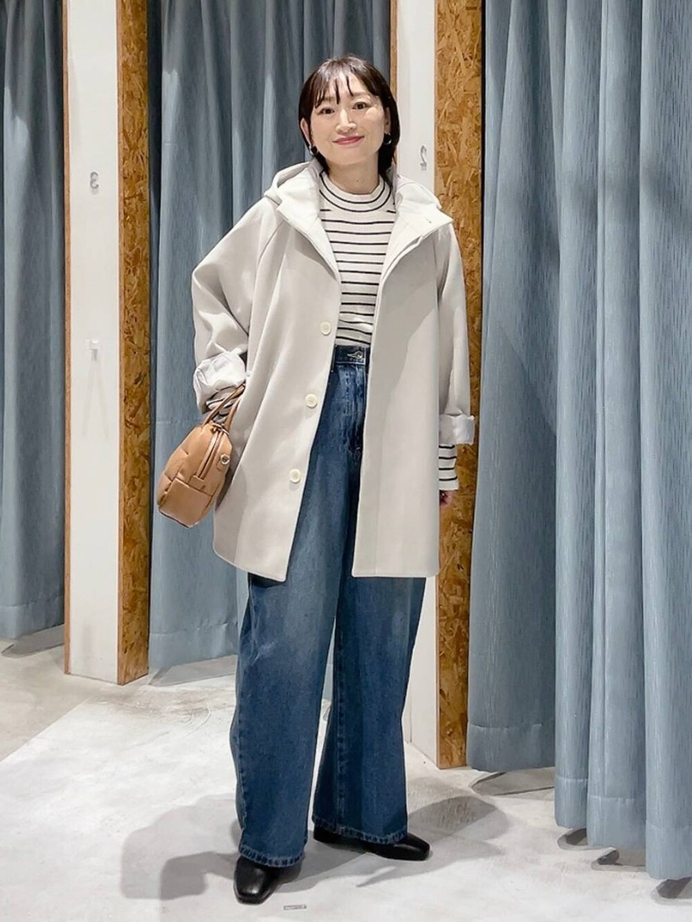 ホワイト系のポンチョ、ホワイト系のニット/セーター、ブルー系のデニムパンツを着用したレディースの秋コーディネートの7枚目の写真