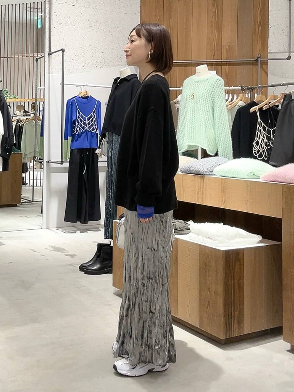 シルバー系のボストンバッグ、ブラック系のニット/セーター、ホワイト系のTシャツ/カットソーを着用したレディースの秋コーディネートの5枚目の写真