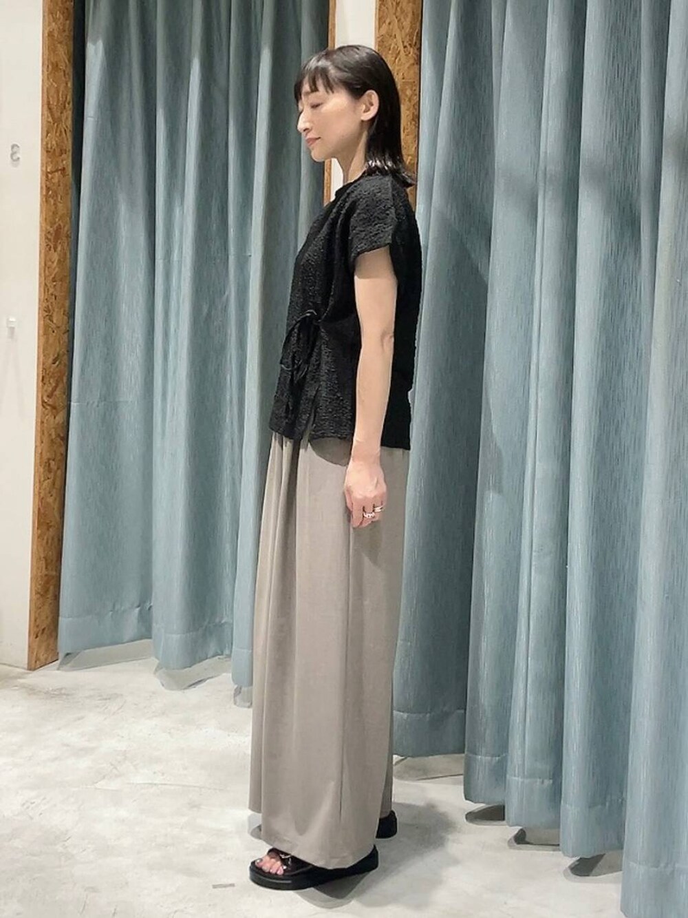 ブラウン系のサンダル、ベージュ系のその他パンツ、ブラック系のTシャツ/カットソーを着用したレディースの夏コーディネートの6枚目の写真