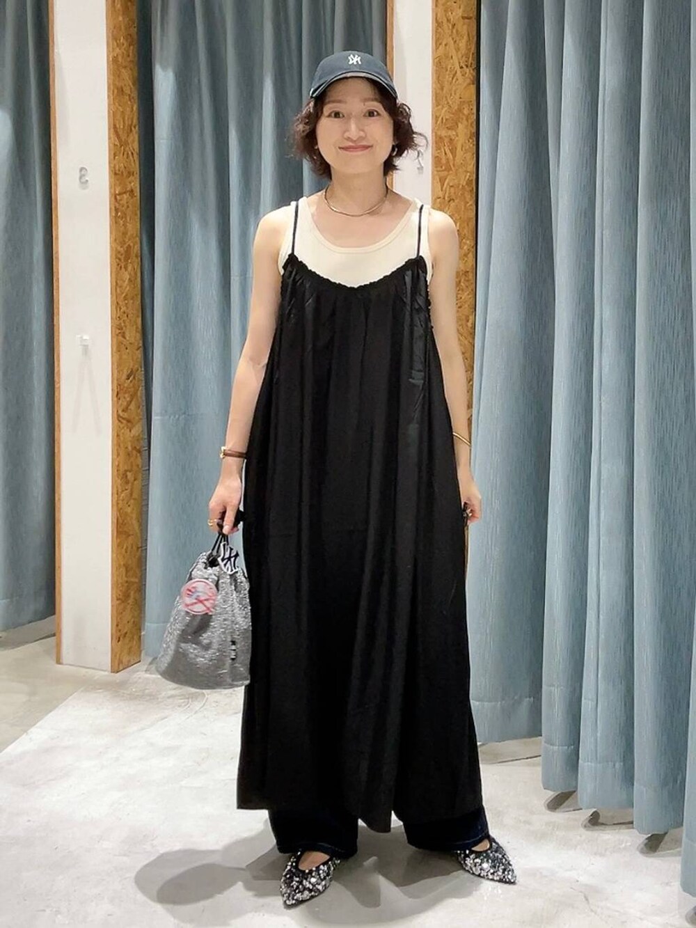 グレー系のショルダーバッグ、ブルー系のデニムパンツ、ホワイト系のタンクトップを着用したレディースの夏コーディネートの2枚目の写真