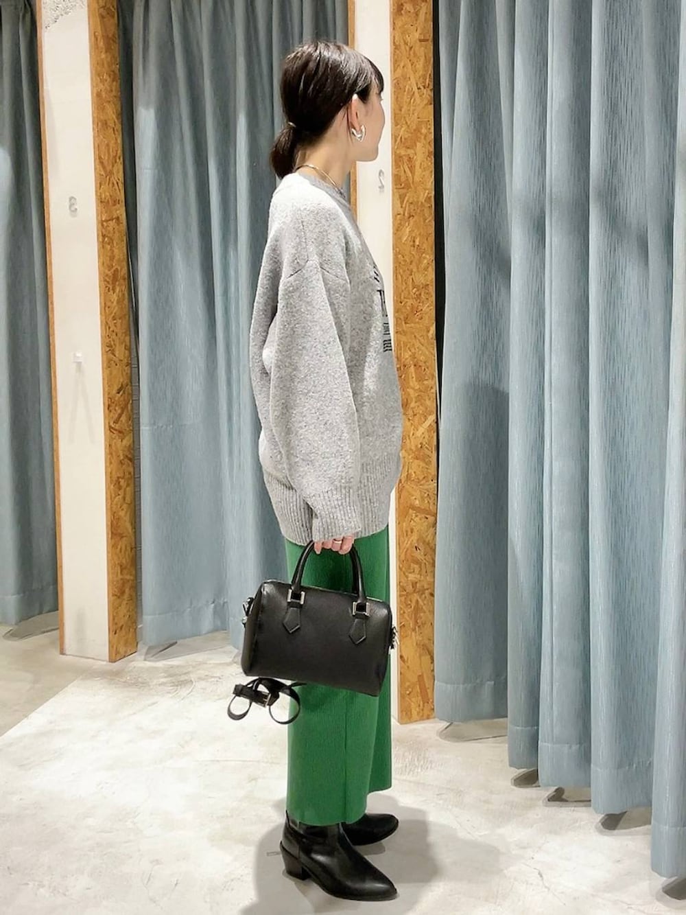 ブラック系のボストンバッグ、ブラック系のブーツ、グレー系のニット/セーターを着用したレディースの冬コーディネートの5枚目の写真