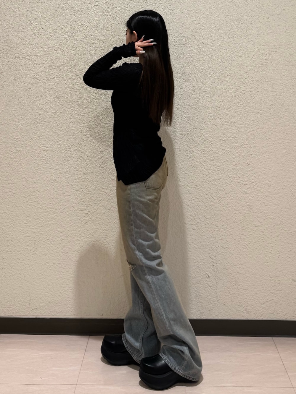 ブルー系のデニムパンツ、ブラック系のブーツ、ブラック系のニット/セーターを着用したレディースの春コーディネートの2枚目の写真