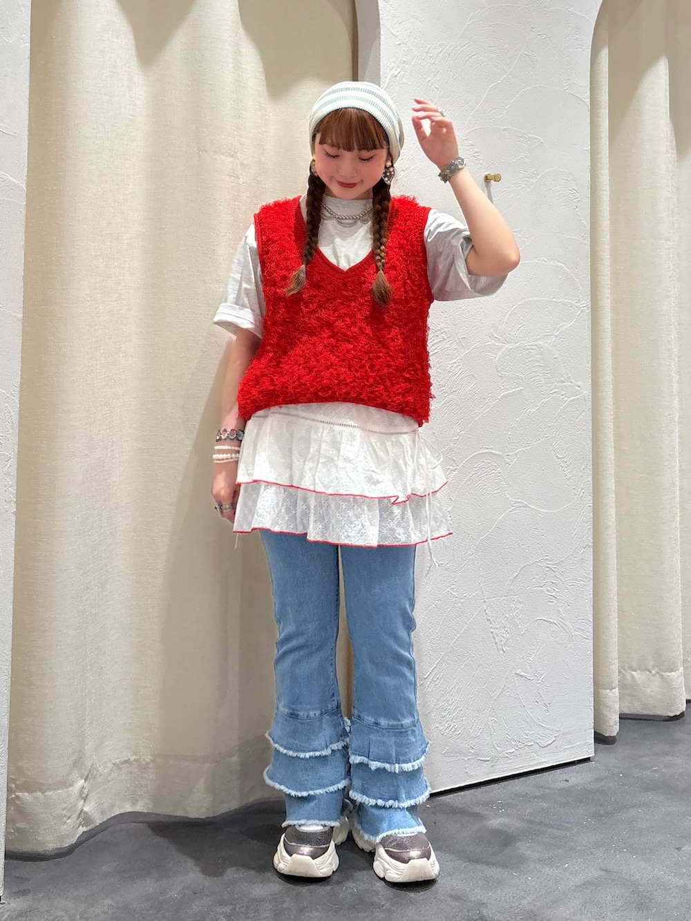 レッド系のベスト、ホワイト系のスカート、ブルー系のデニムパンツを着用したレディースの夏コーディネートの2枚目の写真