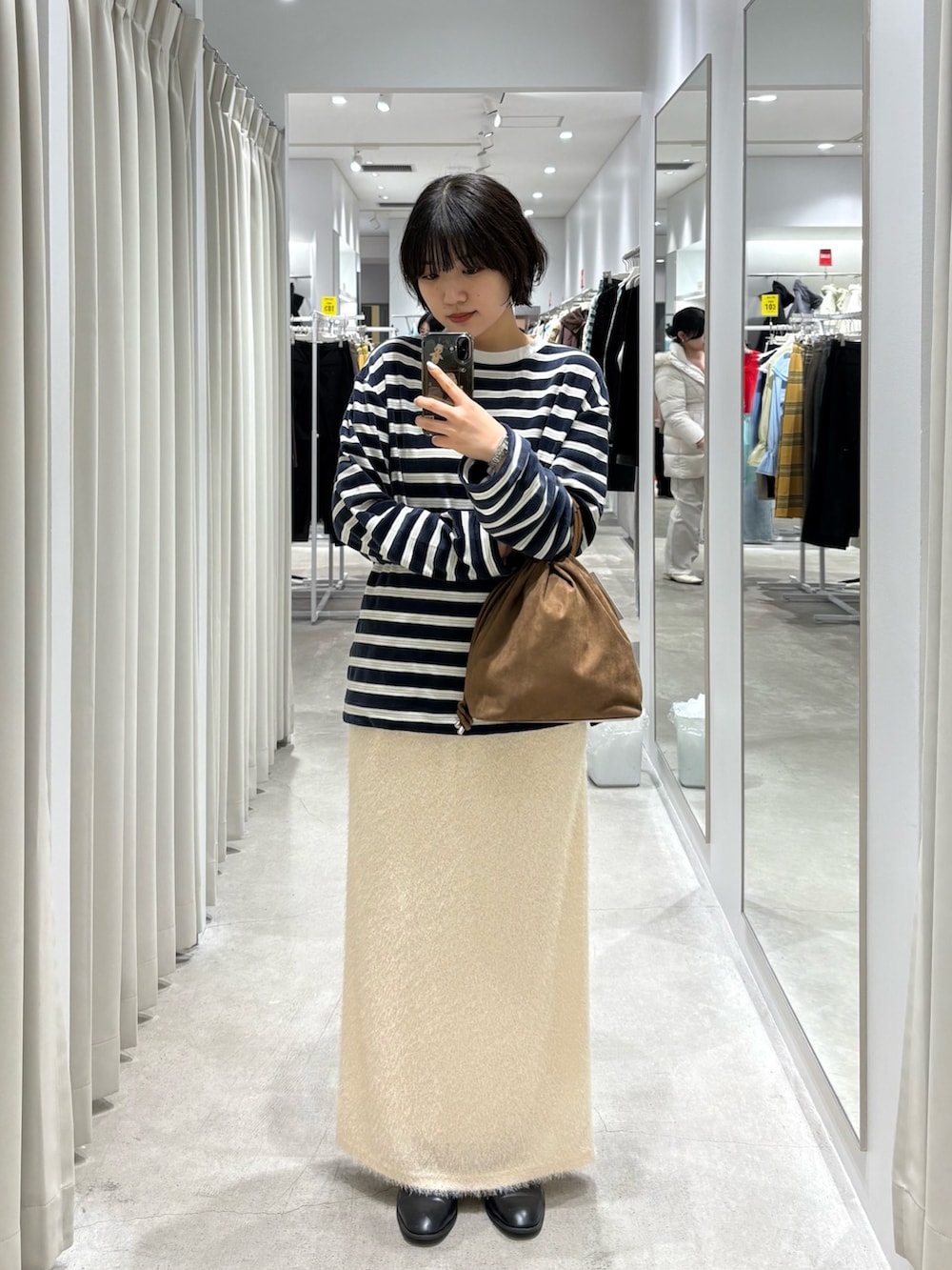 ブルー系のTシャツ/カットソー、ブラウン系のハンドバッグ、ホワイト系のスカートを着用したレディースの冬コーディネートの2枚目の写真