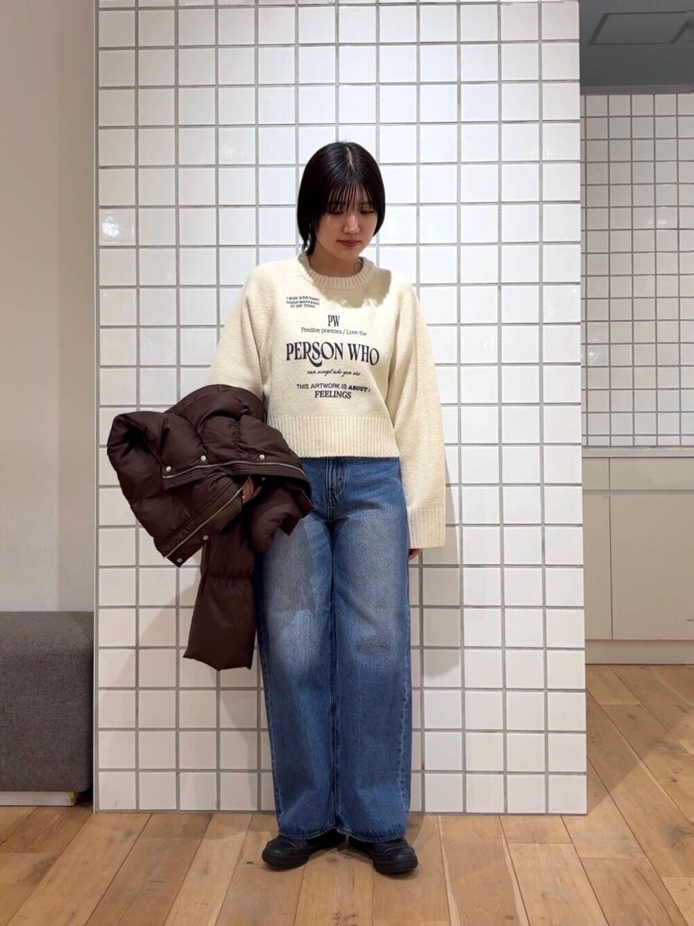 ブラウン系のダウンジャケット/コート、ブルー系のデニムパンツ、ホワイト系のニット/セーターを着用したレディースの冬コーディネートの3枚目の写真