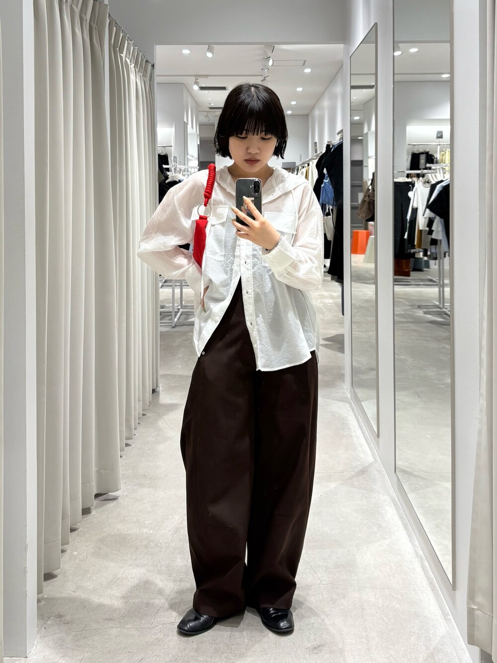 レッド系のハンドバッグ、ホワイト系のシャツ/ブラウス、ブラウン系のその他パンツを着用したレディースの春コーディネートの2枚目の写真