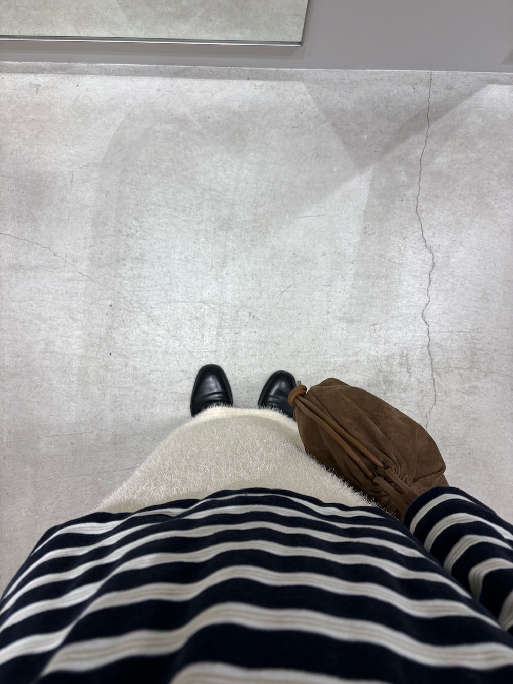 ブルー系のTシャツ/カットソー、ブラウン系のハンドバッグ、ホワイト系のスカートを着用したレディースの冬コーディネートの3枚目の写真