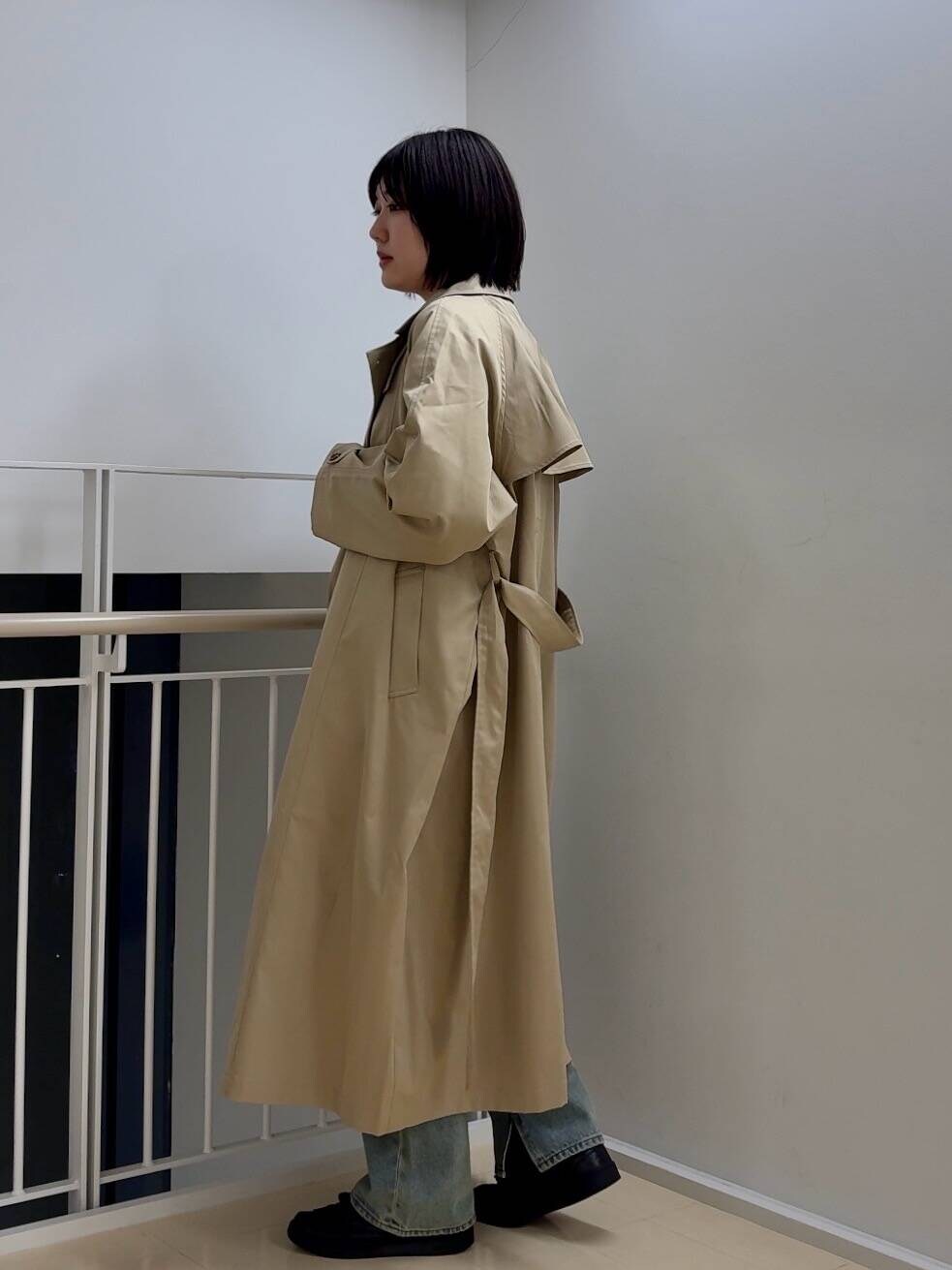 ブルー系のデニムパンツ、ベージュ系のトレンチコート、ブラック系のTシャツ/カットソーを着用したレディースの春コーディネートの2枚目の写真