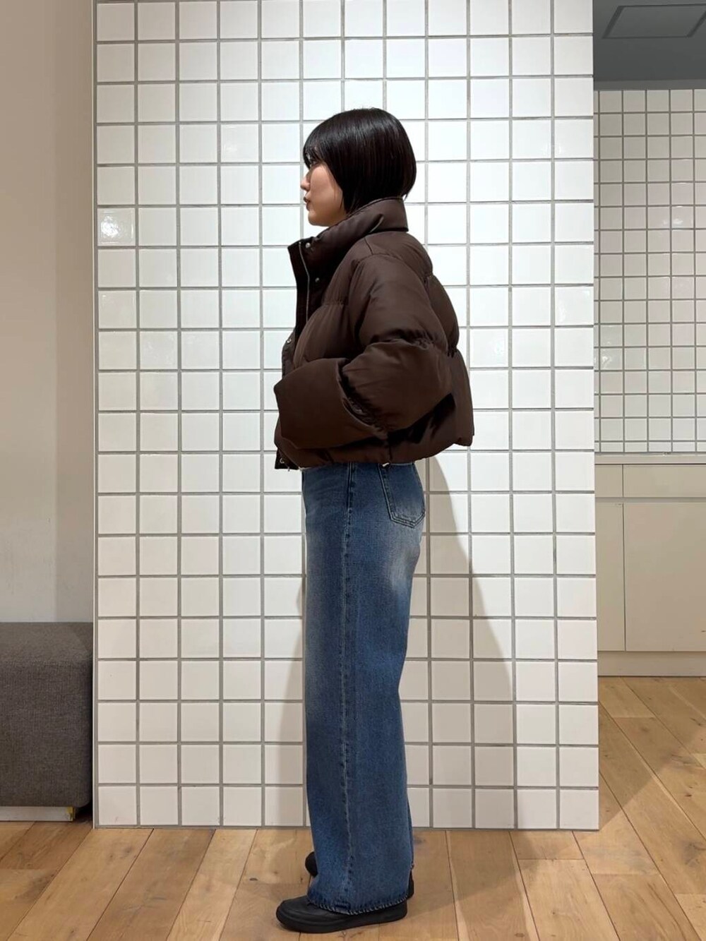 ブラウン系のダウンジャケット/コート、ブルー系のデニムパンツ、ホワイト系のニット/セーターを着用したレディースの冬コーディネートの2枚目の写真