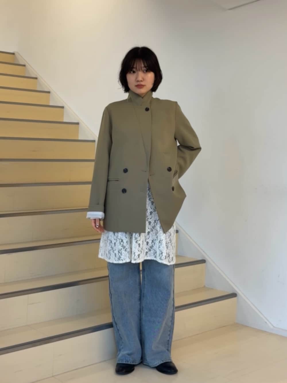 ベージュ系のテーラードジャケット、ホワイト系のキャミソール、ブルー系のデニムパンツを着用したレディースの春コーディネートの2枚目の写真