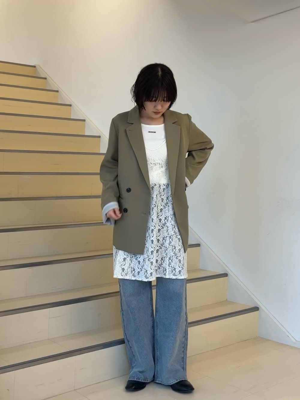 ベージュ系のテーラードジャケット、ホワイト系のキャミソール、ブルー系のデニムパンツを着用したレディースの春コーディネートの3枚目の写真