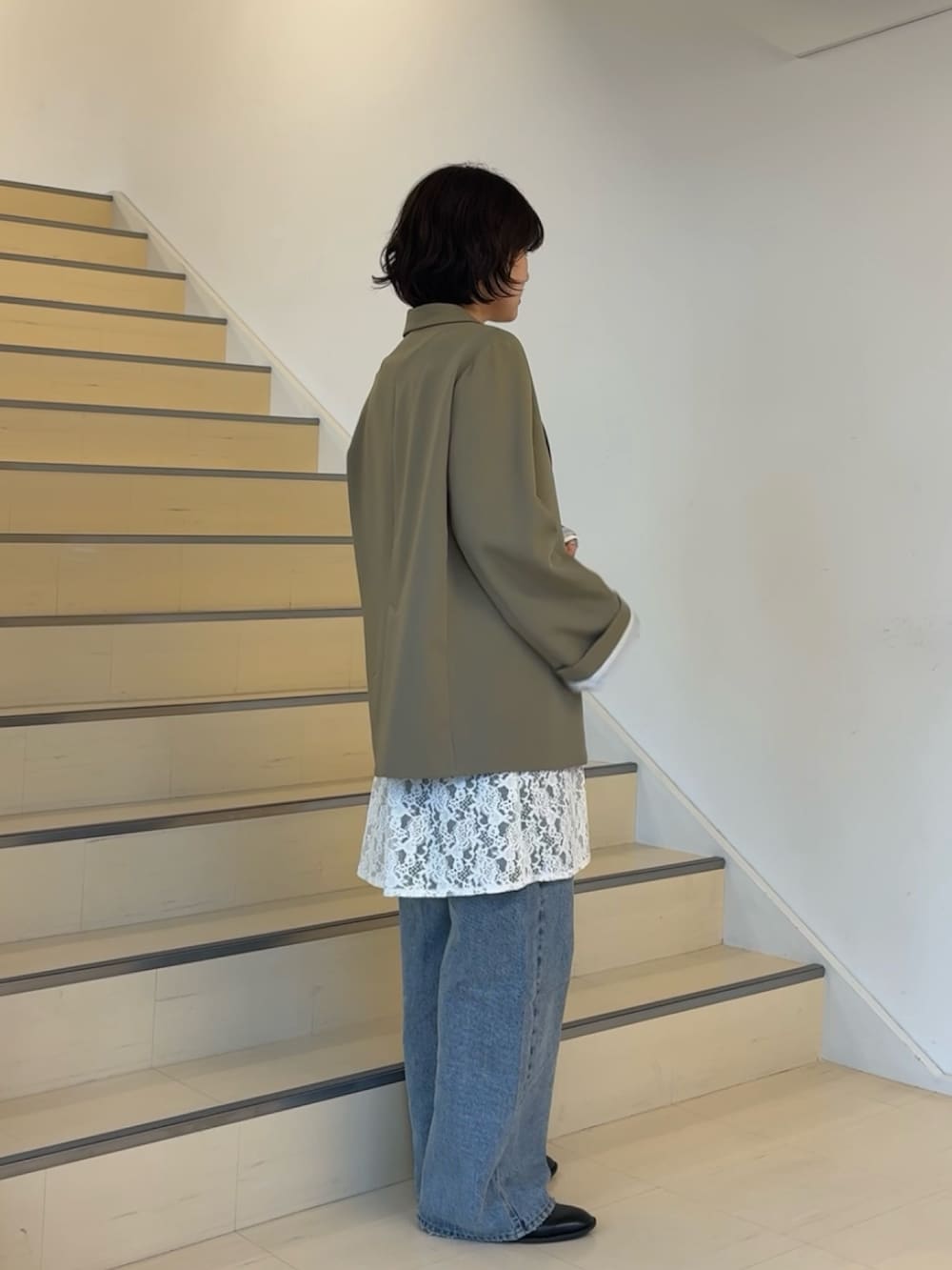 ベージュ系のテーラードジャケット、ホワイト系のキャミソール、ブルー系のデニムパンツを着用したレディースの春コーディネートの4枚目の写真