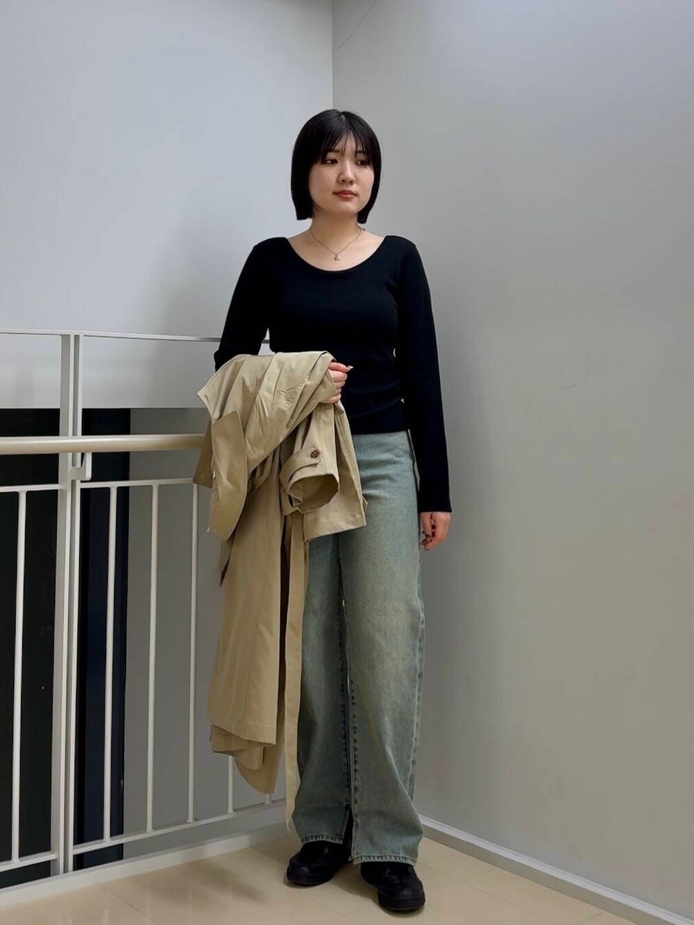 ブルー系のデニムパンツ、ベージュ系のトレンチコート、ブラック系のTシャツ/カットソーを着用したレディースの春コーディネートの3枚目の写真