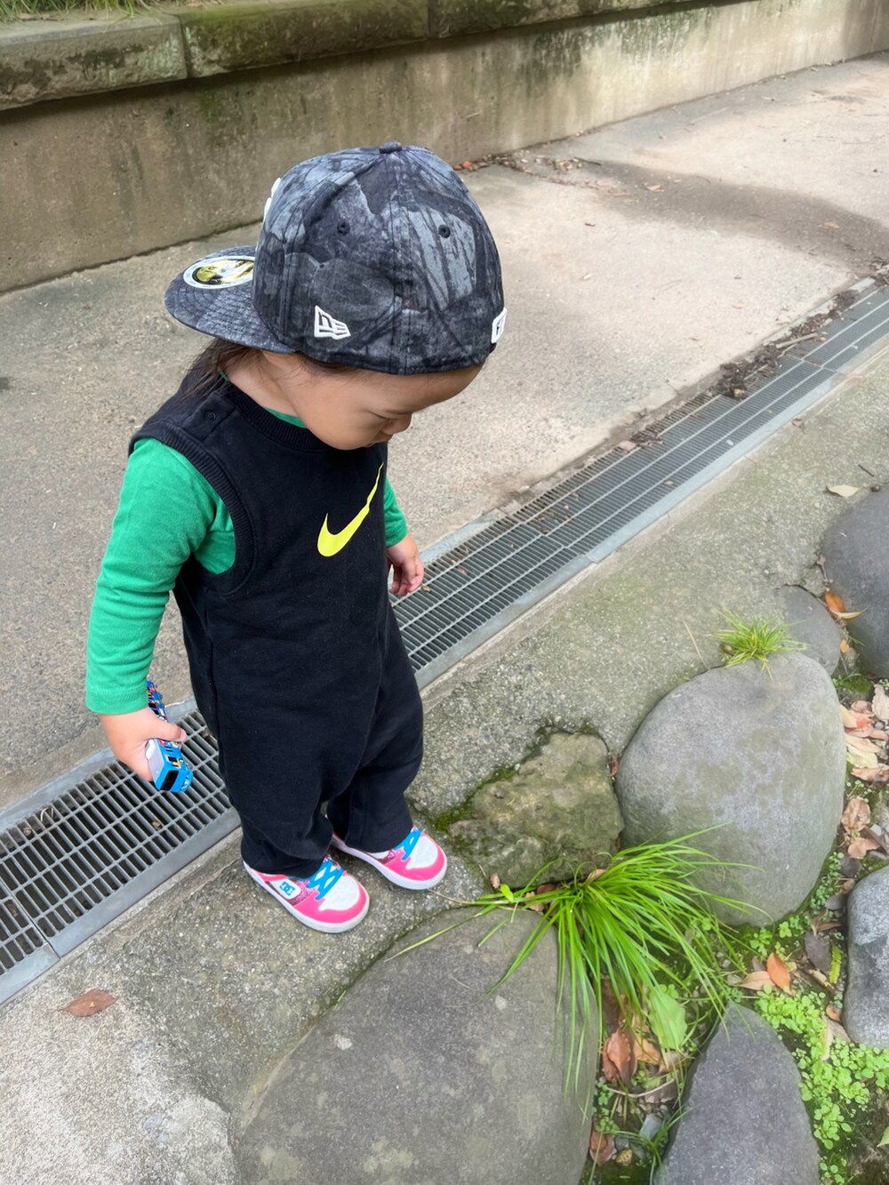 ピンク系のスニーカー、ブラック系のオールインワン・サロペット、グリーン系のTシャツ/カットソーを着用したキッズの秋コーディネートの2枚目の写真