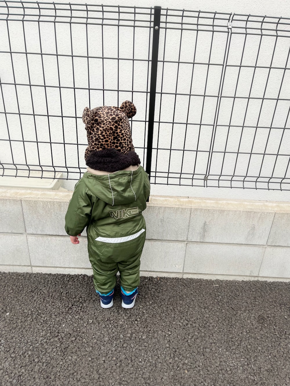 グリーン系のカバーオール、ブルー系のスニーカー、ブラウン系の帽子を着用したキッズの冬コーディネートの2枚目の写真