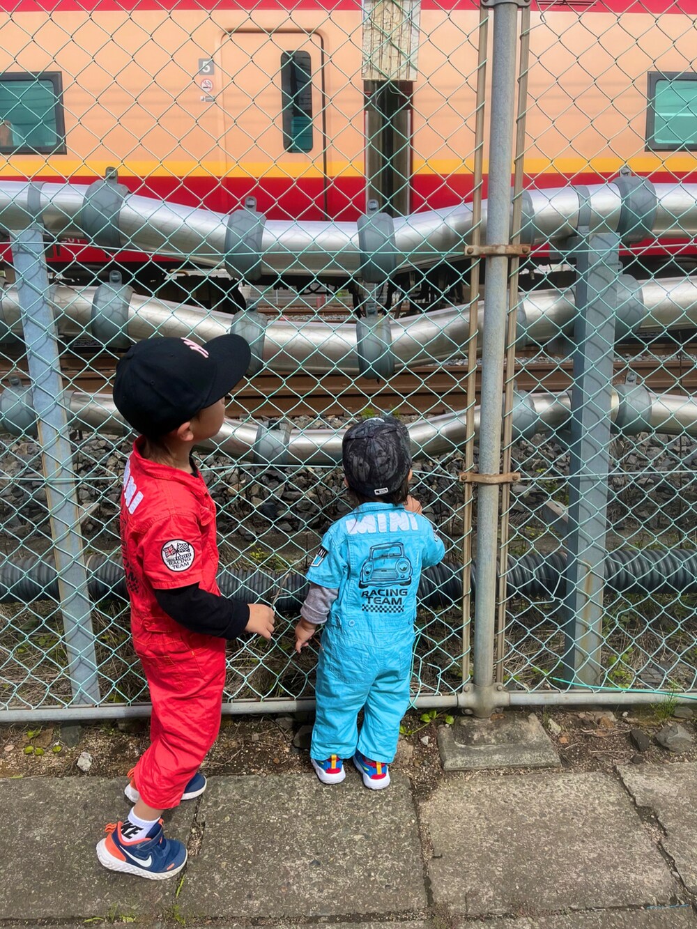 レッド系のオールインワン・サロペット、ブルー系のオールインワン・サロペット、ブルー系のスニーカーを着用したキッズの秋コーディネートの2枚目の写真