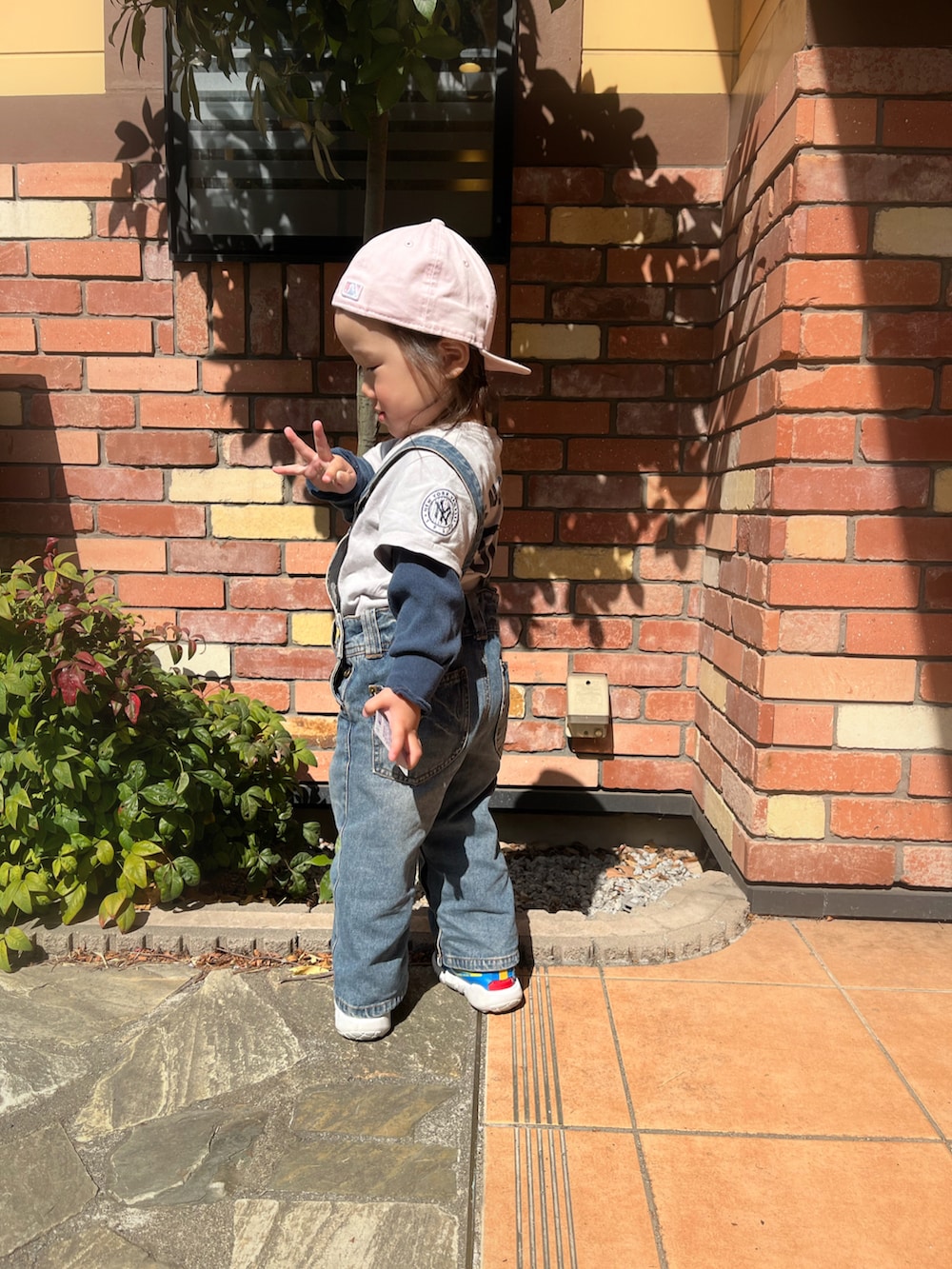 ブルー系のトップス、ブルー系のスニーカー、ピンク系のキャップを着用したキッズの春コーディネートの2枚目の写真