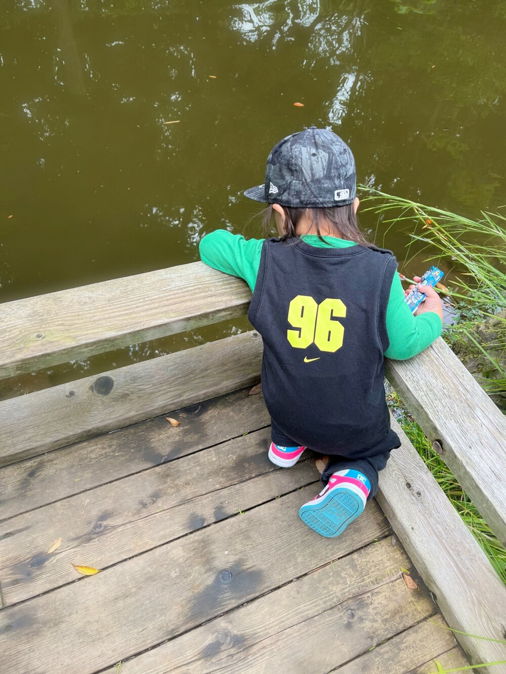 ピンク系のスニーカー、ブラック系のオールインワン・サロペット、グリーン系のTシャツ/カットソーを着用したキッズの秋コーディネートの3枚目の写真