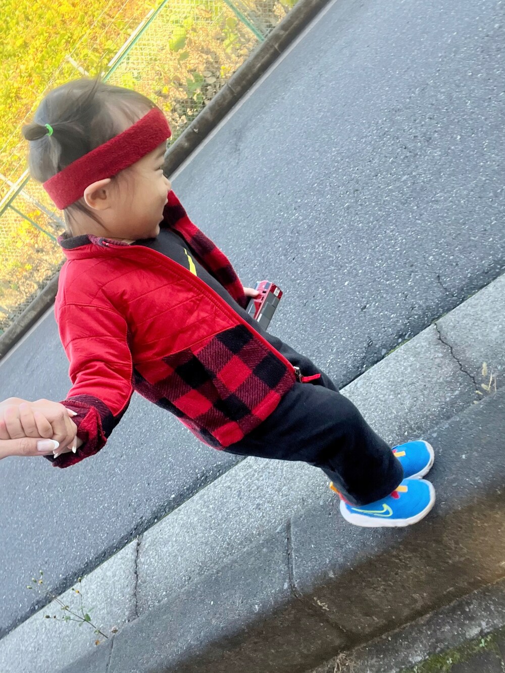 レッド系のジャケット/アウター、ブラック系のオールインワン・サロペット、ブルー系のスニーカーを着用したキッズの冬コーディネートの2枚目の写真