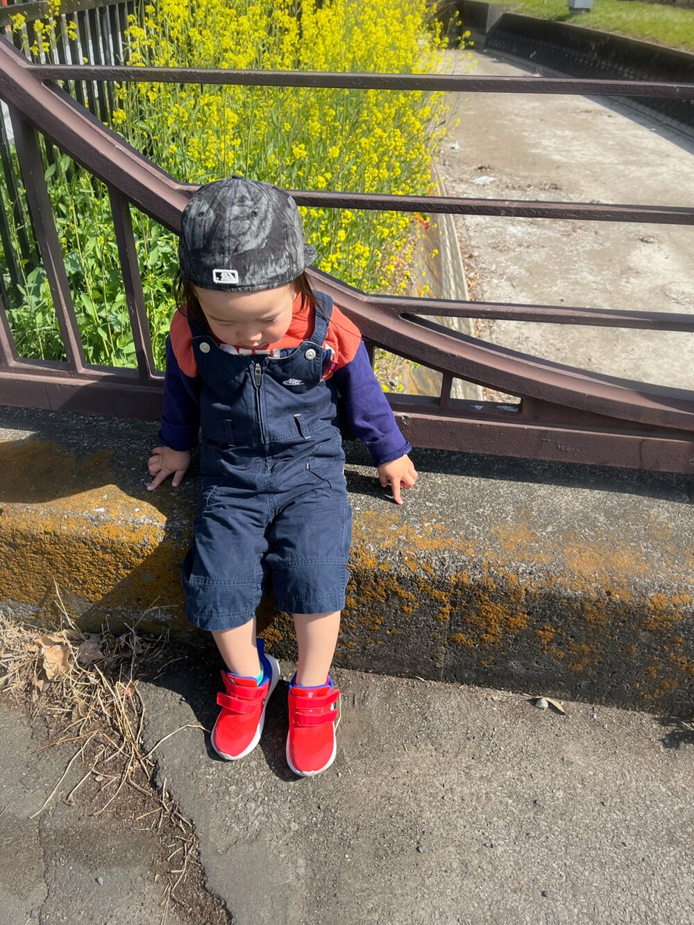 オレンジ系のTシャツ/カットソー、ブルー系のオールインワン・サロペット、オレンジ系のスニーカーを着用したキッズの春コーディネートの2枚目の写真