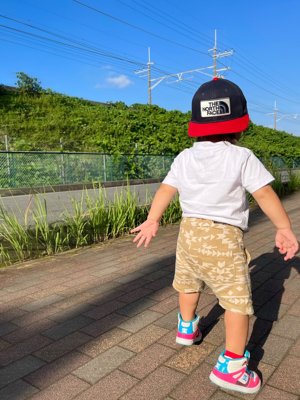 ピンク系のスニーカー、ベージュ系のその他パンツ、ホワイト系のTシャツ/カットソーを着用したキッズの秋コーディネートの2枚目の写真