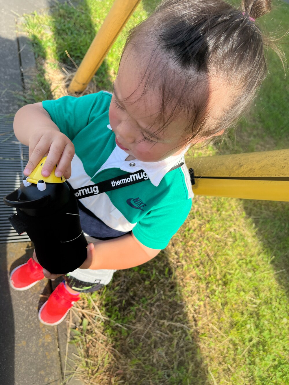 グリーン系のポロシャツ、ブラック系のパンツ、オレンジ系のスニーカーを着用したキッズの春コーディネートの3枚目の写真