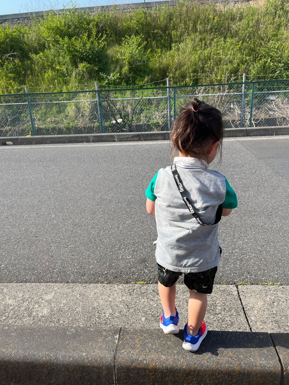 グリーン系のポロシャツ、ブラック系のパンツ、オレンジ系のスニーカーを着用したキッズの春コーディネートの2枚目の写真