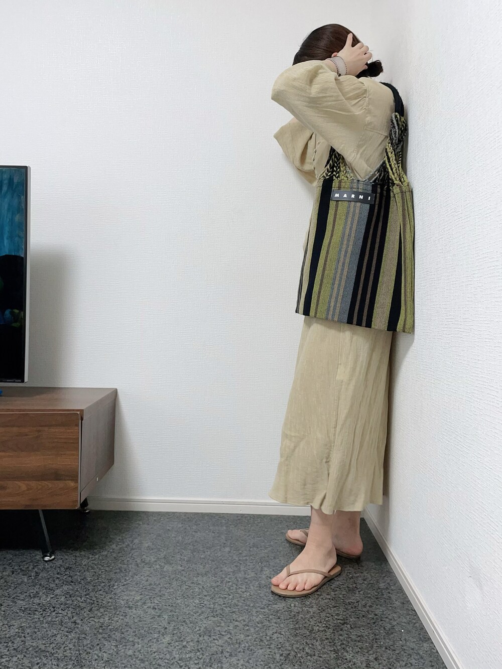 ベージュ系のワンピース、グリーン系のトートバッグ、ベージュ系のサンダルを着用したレディースの春コーディネートの2枚目の写真